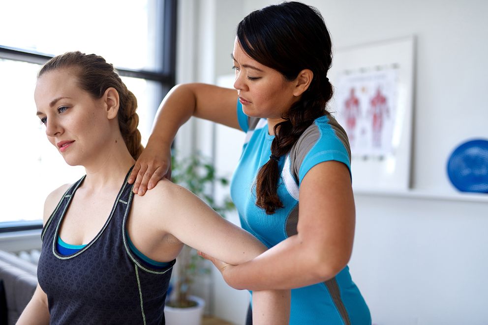 Woman performing physical therapy on a woman's shoulder