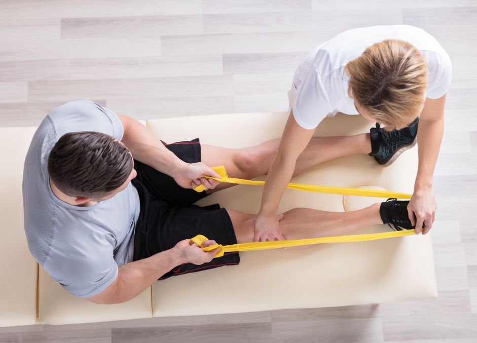 Overhead view of a physical therapist using a band for a man's knee